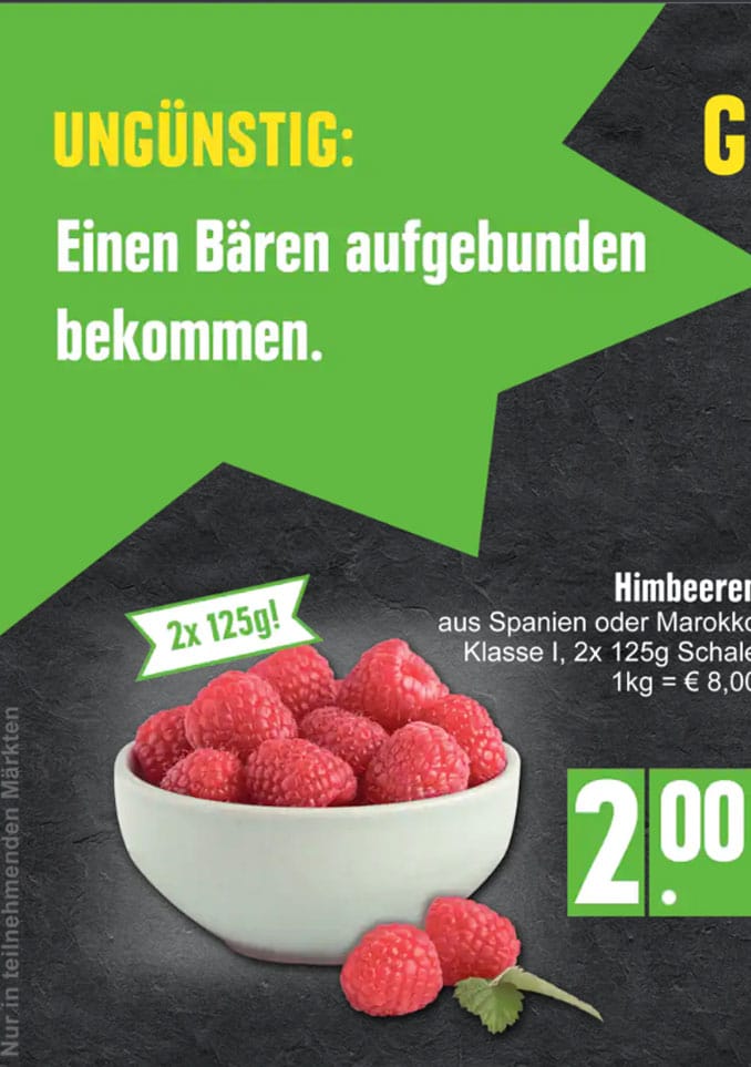 Auf einem dunklen Untergrund steht eine weiße Schale gefüllt mit frischen Himbeeren, darüber befinden sich grün-gelbe Werbetexte und Preisangaben in deutscher Sprache.