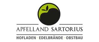 Sartorius Das Logo für Apfelland Sartorius zeigt einen stilisierten Apfel in einem grün-schwarzen Kreis, darunter den Text mit der Aufschrift „Hofladen · Edelbrände · Obstbau“.